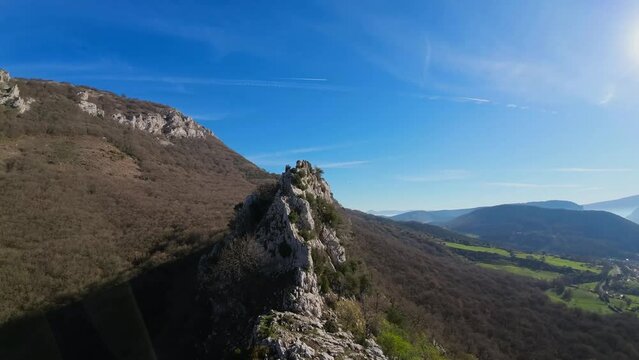 A drone flies over a rocky area on the top of a mountain and suddenly a bird or vulture gets scared and starts to fly. Beautiful image of nature, sunny day