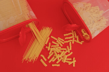 Raw pasta on red background