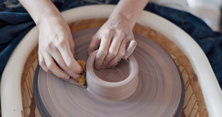 Fototapeta premium Pottery, art and hands on a potter wheel with artist spinning clay in creative class, workshop or studio. Creativity, handicraft and closeup of a sculptor working on ceramic design, craft or creation