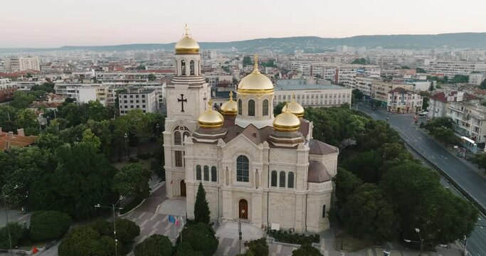 Aerial view Cathedral in historical center of city of Varna, Bulgaria in summer at sunrise in sun drone. Golden dome of church glitters reflecting sunbeams. Symbol of architecture of city of Varna