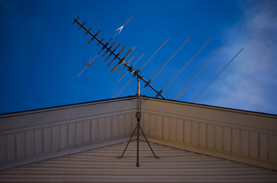 Looking up at a television antenna on the roof of a house