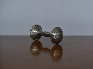 Closeup of a vintage silver baby rattle on a reflective surface