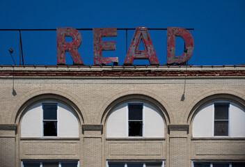 Obraz premium Old large red letters on the roof of an abandoned factory, spelling READ
