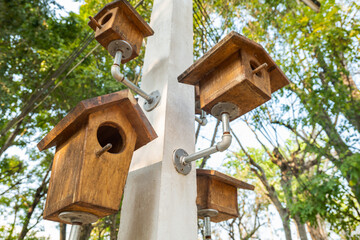 Many old wooden bird houses held with metal pipes on the concrete pole in the garden