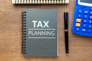 Tax topic on small black notebook on the wooden table, tax payment plan, and calculating