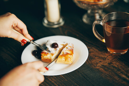 Close up image of a woman eating cherry pastries with fork and knif in cafe