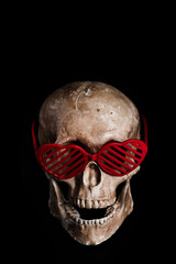 Model of a human skull with glasses with symbolic human hearts on a black background