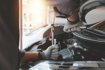 Close-up hand auto mechanic using the wrench to repairing car engine problem. Concepts of check and fix car and maintenance servicing.