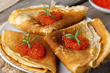 Stack of russian thin pancakes blini with red caviar on an old wooden table. Maslenitsa, traditional Russian blini