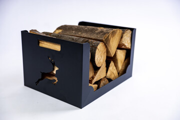 A metal box for firewood with wood logs in it on white background in a studio photoshoot.
