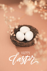 Easter concept with Happy Easter lettering. Eggs on a beige background. Nest containing three white egg.