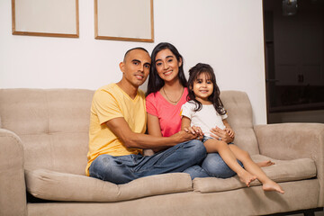 A latin american family together in a sofa. - obrazy, fototapety, plakaty