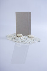 Grey notebook on a mountain stack of white rocks. Beautiful studio product photoshoot.