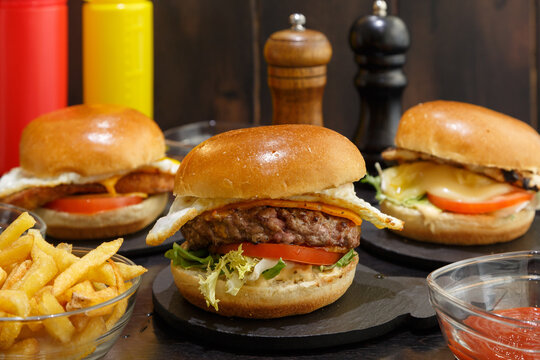 Trois Burgers avec des frites et sauce tomate fait maison sur une table en bois rustique