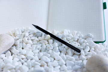 Notebook and pen on white studio background. White rocks falling in front of it. Beautiful composition of notebook, pen. High quality photo