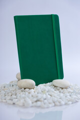 Green notebook on a mountain stack of white rocks. Beautiful studio product photoshoot. High quality photo