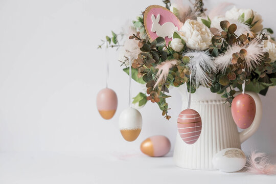 Banner. The concept of a bright Easter holiday. A bouquet of flowers with feathers and white rabbits on a white isolated background. Beautiful Easter card.