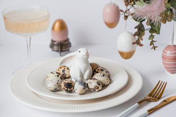 Banner. The concept of a bright Easter holiday. A bouquet of flowers with feathers, white rabbits and Easter eggs in a plate on a white isolated background. Beautiful Easter card.