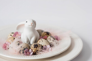 Banner. The concept of a bright holiday is a white rabbit and Easter quail eggs with pink flowers...