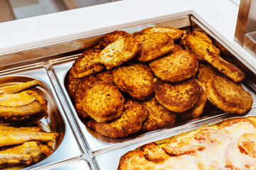 Meat cutlets on a metal baking sheet in a fast food canteen. An assortment of dishes in a small cafe or eatery. Close-up