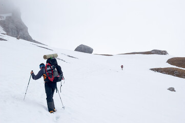 Snow hiker walking in a snowy hillside in a cloudy day