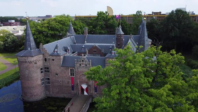 Rising aerial reveal of a historic castle surrounded by a moat in the Netherlands