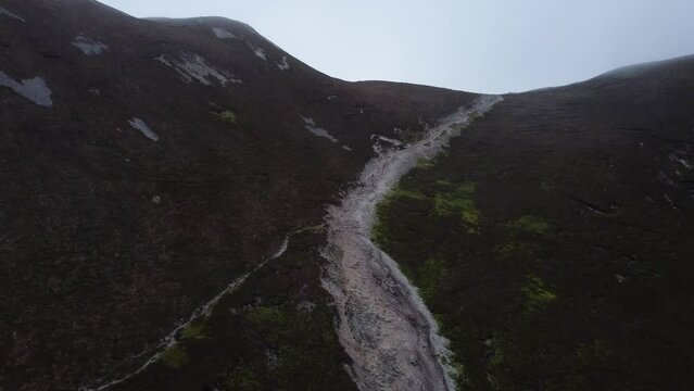 Aerial of people descending mountain trail in Ireland