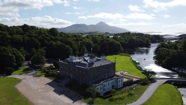 Rising aerial shot of Georgian estate in Irish countryside next to mountains and river