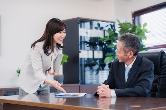 役員に報告をする秘書の女性