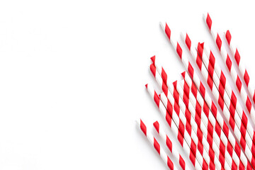 Paper drinking straws with red stripes ornament on a white background, flat lay.