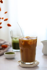 
Close up of a cup of iced coffee with milk, milk jug, matcha powder and a cup of matcha green tea in the afternoon sun on table.
Iced coffee and green matcha on a light blurred background. Food trend