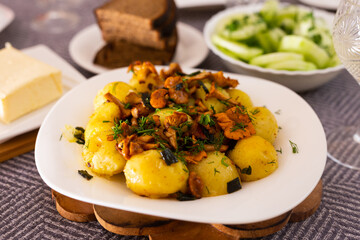 baked potatoes with chanterelles, served with herbs on white plate
