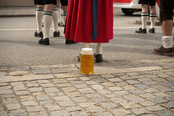 A one liter beer glass stands behind a womans feet