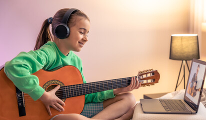Little girl learns to play the guitar, online music video lesson.
