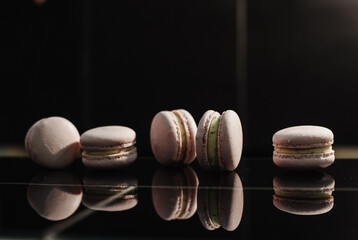 French pink macarons on a black background. Raspberry macaron with white ganache filling. French meringue cookies macaron. Dark background. film noise