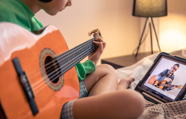 Little girl learns to play the guitar, online music video lesson.