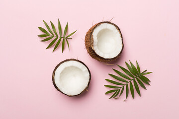 Coconut with leaves on color background, top view