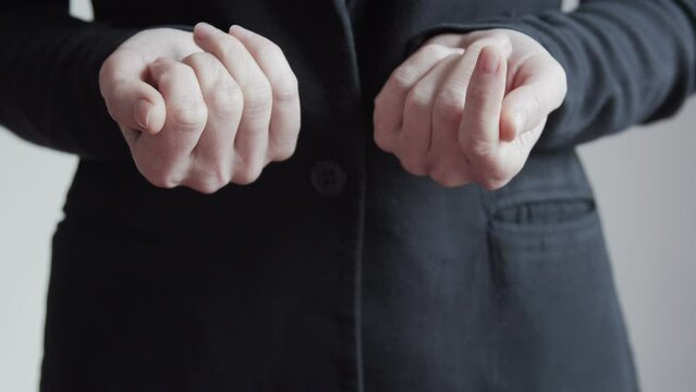 The woman approaches with her hands clenched into fists. The fists open and the chess pieces of the white pawn and the black queen lie on the palms.