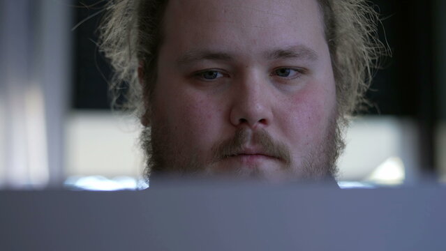 Close Up Face Man Working In Front Of Computer Screen With Serious Expression. Concentrated Male Person Staring At Laptop Focused On Task