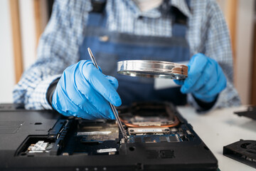 Female engineer repairing and upgrade laptop computer in service center. Worker with tools....