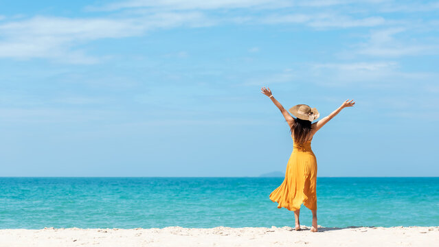 Summer vacations. Lifestyle woman relax and chill on beach background.  Asia happy young people with white dress raise arm on the wave sea, summer trips walking enjoy  tropical beach