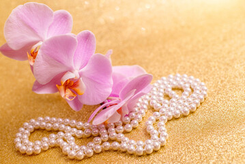 Fototapeta na wymiar purple Orchid and pearl necklace on a shiny gold background 