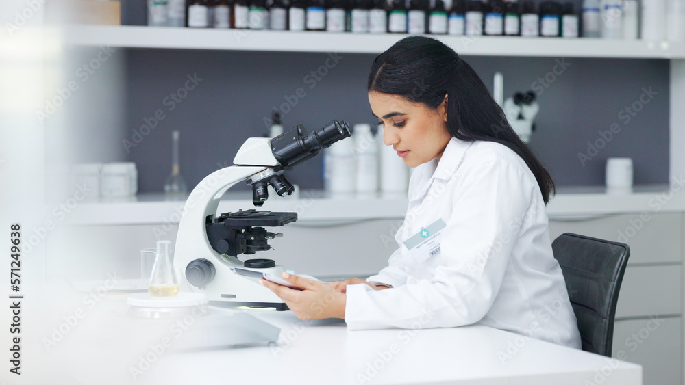 Poster Young scientist using a digital tablet and microscope in a lab. Female pathologist analyzing medical samples while doing experiments to develop a cure. Microbiologist conducting forensic research