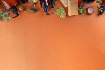 Natural organic skin care flat lay. Natural organic beauty cosmetic products on golden beige background: hand lotion, face cream in jar, essential oil, skin roller, with eucalyptus and tea tree leaves