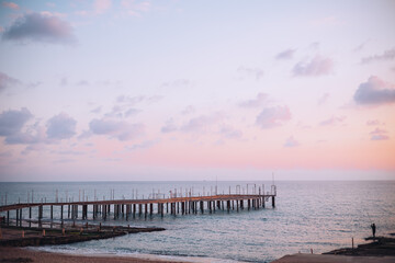 Naklejka premium Magic purple sunset over sea, sunset with little fluffy clouds, fisherman's silhouette