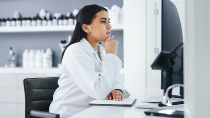 Young scientist using a computer and microscope in a lab. Female pathologist analyzing medical...