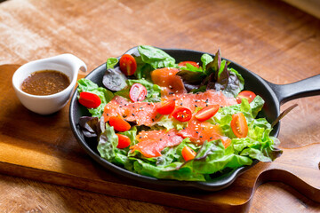 Smoke salmon Salad with green and red oak and cherry tomato served with sesame salad dressing. Homemade food. The concept for a tasty and healthy meal.