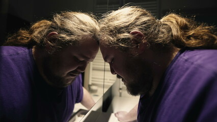 One desperate young overweight man crying in bathroom alone. Desperate tearful person leaning on...