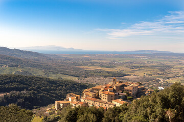 Italy Grosseto Maremma, route in MTB and EMTB in the woods of Gavorrano up to Mount Calvo, panoramic view of the village and the valley to the sea, Elba Island in the background