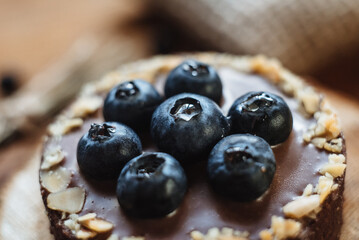 Delicious tartlet with chocolate and fresh blueberries, close-up. A refined European dessert.